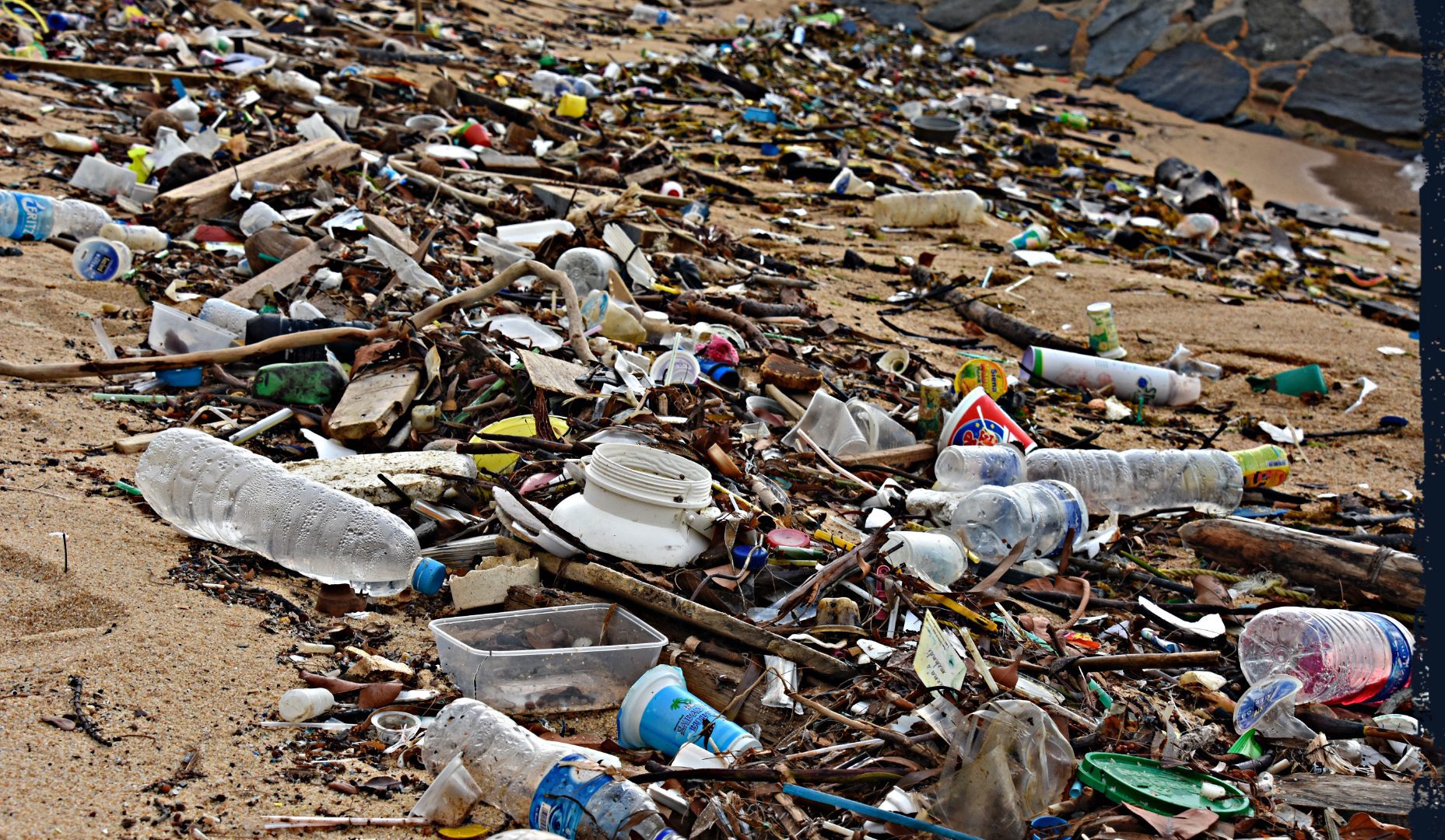 A beach littered, amongst other things, with dozens of waste plastic bottles