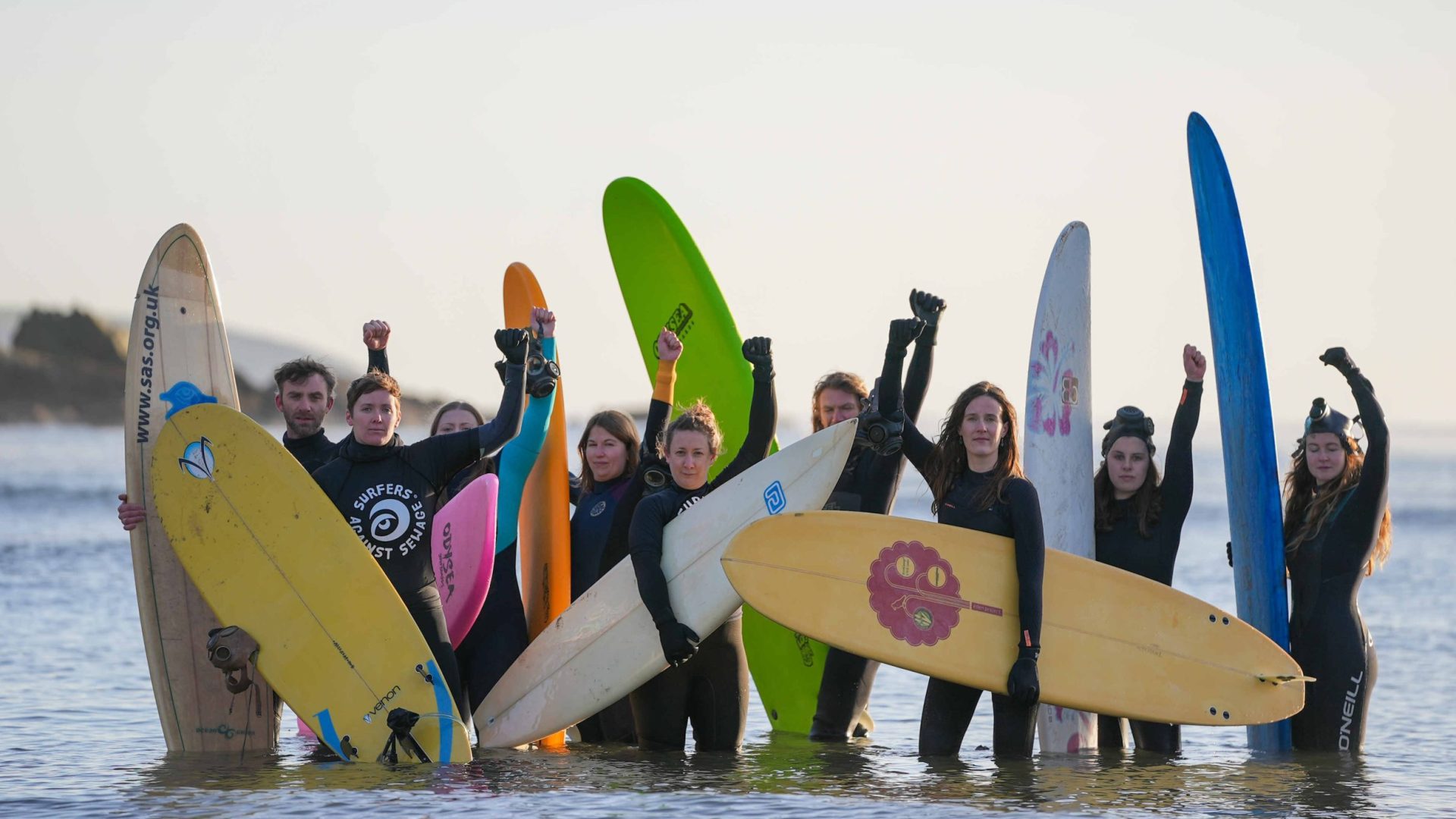 Surfers in the ocean with raised fists